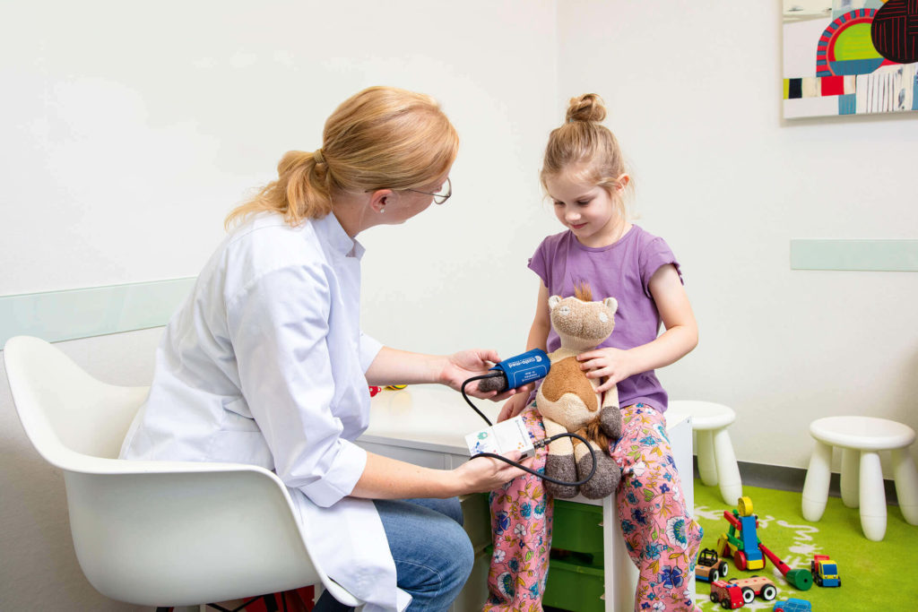 Ärztin misst den Blutdruck vom Kuscheltier des kleinen Mädchens